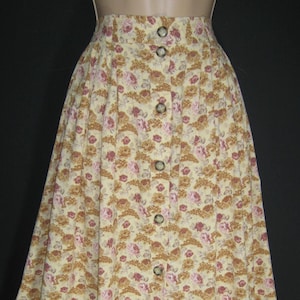 May include: A long, button-down skirt with a floral pattern in shades of yellow, pink, and brown. The skirt has a high waist and brown buttons down the front. The fabric appears to be a lightweight material.
