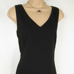 May include: A black sleeveless dress with a v-neckline. The dress is made of a smooth, silky fabric and has a fitted silhouette.