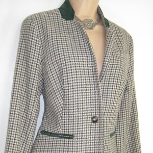 May include: A brown and black houndstooth patterned blazer with a green velvet collar and trim. The blazer has a single button closure and long sleeves.