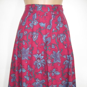 May include: A long, flowing skirt with a floral print. The skirt is a deep red color with blue and green floral designs. The skirt has a waistband and a pleated design.