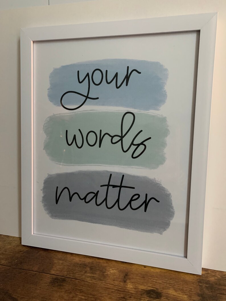 K&ouml;nnte beinhalten: Wei&szlig;er gerahmter Druck mit dem Text "your words matter" in schwarzer kursivschrift auf einem Hintergrund aus drei horizontalen blauen und gr&uuml;nen Aquarellstrichen.