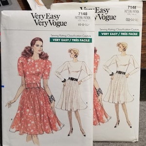 May include: Two sewing patterns for dresses, both labeled "Very Easy Very Vogue." The pattern on the left shows a pink floral dress with short sleeves and a belt. The pattern on the right shows a white dress with long sleeves and a black belt. Both patterns are labeled "Very Easy/Très Facile."
