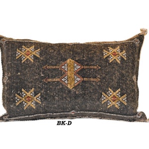 May include: A black and brown patterned throw pillow with geometric designs. The pillow has a fringe border and the text "BK-D" is printed on the bottom.
