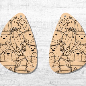 May include: A pair of wooden earrings shaped like teardrops, featuring a black and white line drawing of a variety of cacti with smiling faces.
