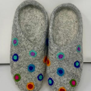 May include: A pair of gray felt slippers with colorful embroidered circles. The slippers have a soft, fuzzy lining.