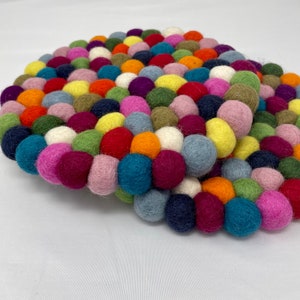 May include: A round, colorful felt ball trivet. The trivet is composed of numerous small felt balls in a variety of colors, including red, orange, yellow, green, blue, purple, and pink. The trivet is designed to protect surfaces from heat.