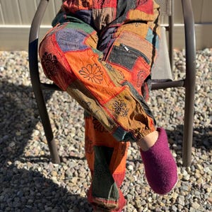 May include: Patchwork trousers with a variety of colours and patterns, including red, orange, green, blue, and brown. The trousers have a loose fit and a drawstring waist.