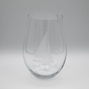 May include: A clear glass wine glass with an etched sailboat design.
