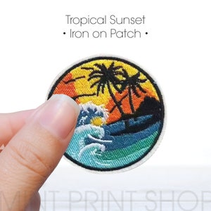 May include: A round iron-on patch with an embroidered design of a tropical sunset scene. The patch features palm trees, a setting sun, and ocean waves in shades of orange, yellow, blue, and green.