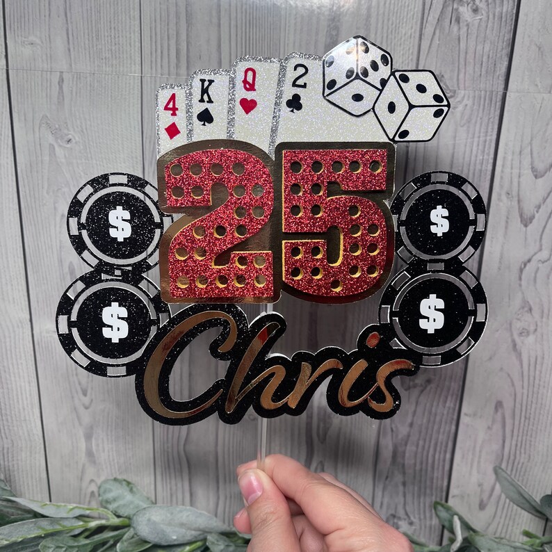 May include: A red and gold glitter cake topper with the number 25 and the name Chris. The topper also features playing cards, dice, and poker chips.