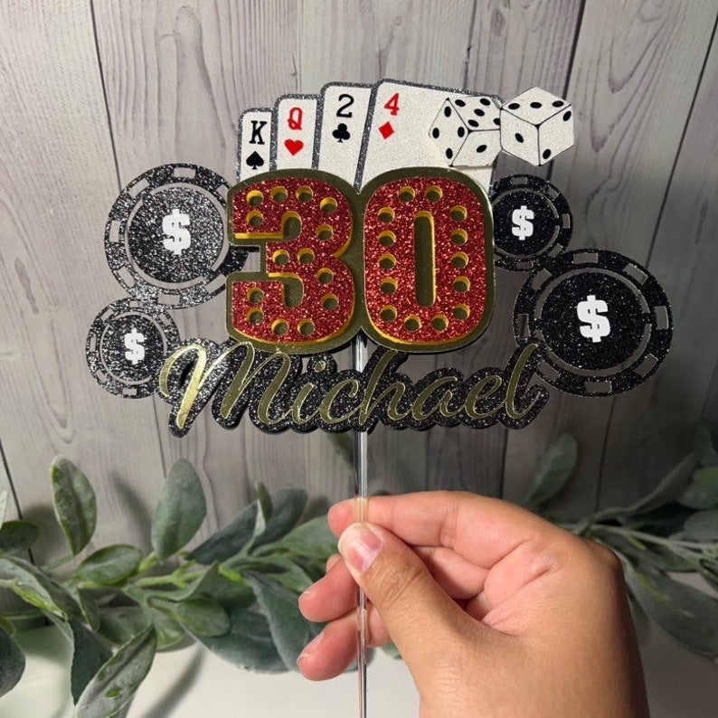 May include: A red and gold glitter cake topper with the number 30 and the name Michael. The topper is decorated with playing cards, poker chips, and dice.