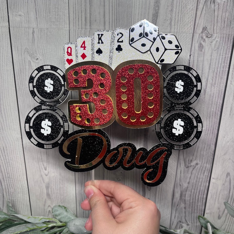 May include: A red and gold glitter cake topper with the number 30, four playing cards, three black and white poker chips with dollar signs, and the name Doug. The cake topper is perfect for a 30th birthday party.