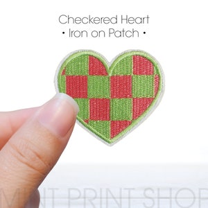 Könnte beinhalten: Ein grünes und rotes kariertes Herzförmiges Bügelbild. "Checkered Heart" und "Iron on Patch" stehen über dem Patch.