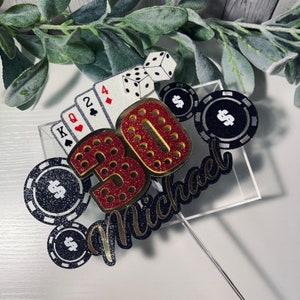 May include: A red and gold glitter 30 with a black and gold glitter "Michael" and black and silver poker chips with dollar signs. The 30 is surrounded by playing cards and dice.