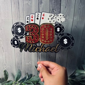 May include: A red and gold glitter cake topper with the number 30, playing cards, dice, and poker chips. The topper also includes the name "Michael".