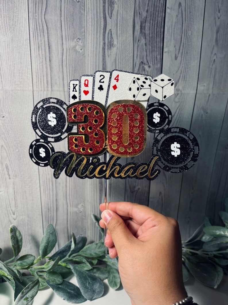 May include: A red and gold glitter cake topper with the number 30, playing cards, dice, and poker chips. The topper also includes the name "Michael".