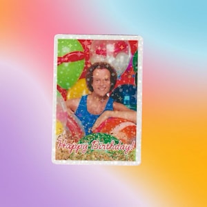 Puede incluir: Una tarjeta brillante con una foto de un hombre con el pelo rizado sonriendo y sosteniendo globos. La tarjeta dice "¡Feliz cumpleaños!" en letras rojas.