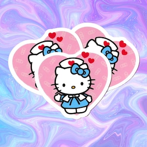 Puede incluir: Tres pegatinas en forma de corazón rosa con un contorno blanco. Cada pegatina presenta una imagen de dibujos animados de Hello Kitty vestida de enfermera con un uniforme azul, un sombrero blanco y un lazo azul. El fondo de cada pegatina es rosa con un patrón blanco de vendas.