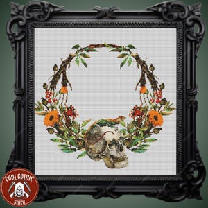 May include: A cross-stitch pattern featuring a skull surrounded by a wreath of flowers and leaves. The skull is white with black details and is surrounded by a variety of flowers in shades of orange, yellow, red, and green.