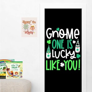 May include: A black door with a green and white sign that says "Gnome One Is Lucky Like You!" with a gnome illustration. There are two books and a picture on the wall next to the door.