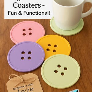 May include: A collection of colorful, button-shaped coasters in pink, yellow, purple, and green. A white mug sits on a green coaster. The text "Big Button Coasters - Fun & Functional!" is displayed. A tag reads "handmade with love cute as a button."