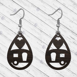 May include: A pair of wooden earrings shaped like teardrops with a camper and heart cutout design. The earrings are brown and have silver hooks.