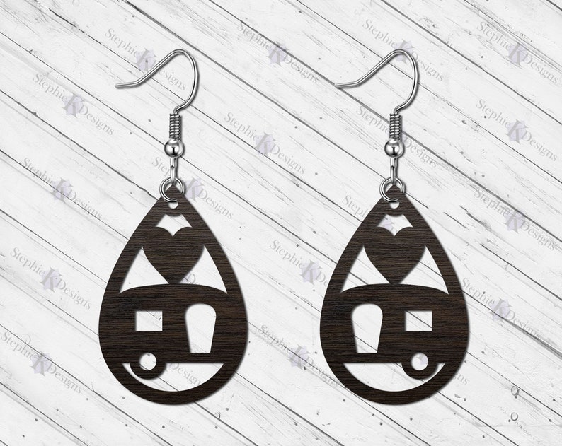 May include: A pair of wooden earrings shaped like teardrops with a camper and heart cutout design. The earrings are brown and have silver hooks.
