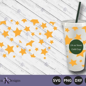 May include: A white 24 ounce cold cup with a green circle that says "24 oz Venti Cold Cup". The cup is decorated with yellow stars on a white background. The cup is sitting on a white wooden surface.