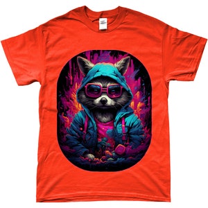 Puede incluir: Una camiseta naranja con un mapache que lleva gafas de sol y una sudadera con capucha azul. El mapache se encuentra sobre un fondo abstracto y colorido con tonos rosas y morados. El dise&ntilde;o est&aacute; encerrado en un &oacute;valo negro.