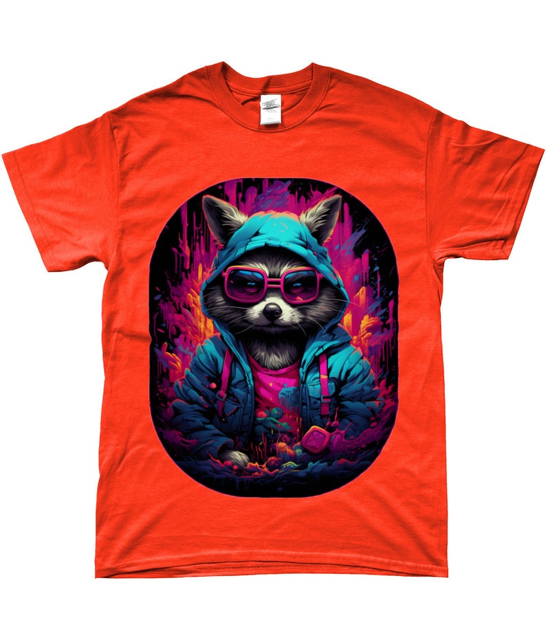 Puede incluir: Una camiseta naranja con un mapache que lleva gafas de sol y una sudadera con capucha azul. El mapache se encuentra sobre un fondo abstracto y colorido con tonos rosas y morados. El dise&ntilde;o est&aacute; encerrado en un &oacute;valo negro.