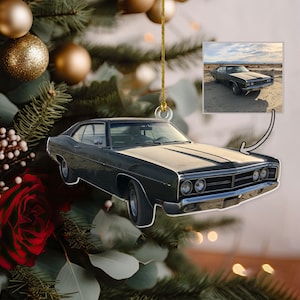 May include: A flat, die-cut Christmas tree ornament shaped like a dark green vintage muscle car. The ornament features a small inset rectangular photograph of the same car parked in a desert landscape, connected by a thin black arrow graphic.