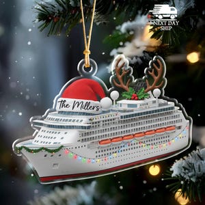 May include: A cruise ship Christmas ornament with a red Santa hat and reindeer antlers. The ornament is white with colorful lights and the text "The Millers". A gold string is attached for hanging.