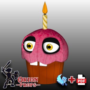 May include: A pink and orange cupcake with a single candle on top. The cupcake has a face with large eyes and a toothy grin. The cupcake is a papercraft model.