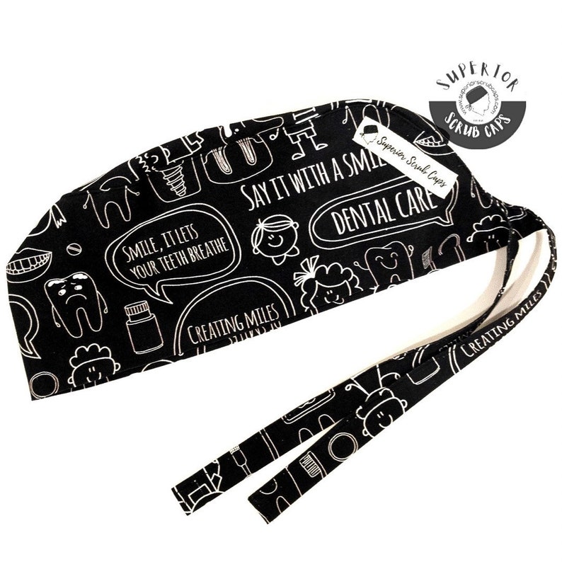 May include: Black scrub cap with a white dental themed print. The print includes teeth, toothbrushes, toothpaste, and the text "Smile, it lets your teeth breathe" and "Say it with a smile, Dental Care".