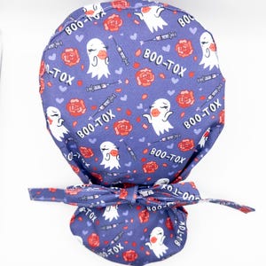 May include: A purple scrub hat with a pattern of white ghosts, red roses, and the text "BOO-TOX".