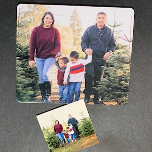 May include: A family of four walking through a Christmas tree farm. The parents are holding hands with their two young sons. The family is wearing casual clothing and smiling.