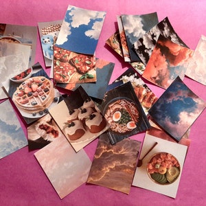 Może przedstawiać: Kolekcja kolorowych kart z obrazami jedzenia i chmur. Karty są ułożone w losowym wzorze na r&oacute;żowym tle. Obrazy jedzenia obejmują gofry, ramen, pizzę i miskę ryżu. Obrazy chmur są w r&oacute;żnych odcieniach niebieskiego i szarego.