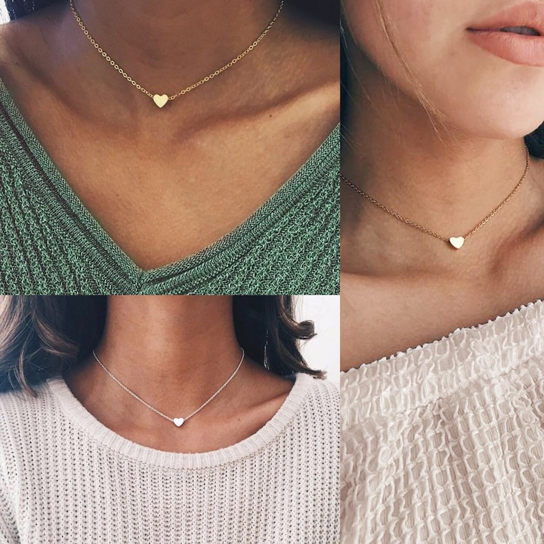 May include: Three images of a simple gold heart necklace on a model wearing a green, white, and white shirt. The necklace is delicate and features a small heart pendant.