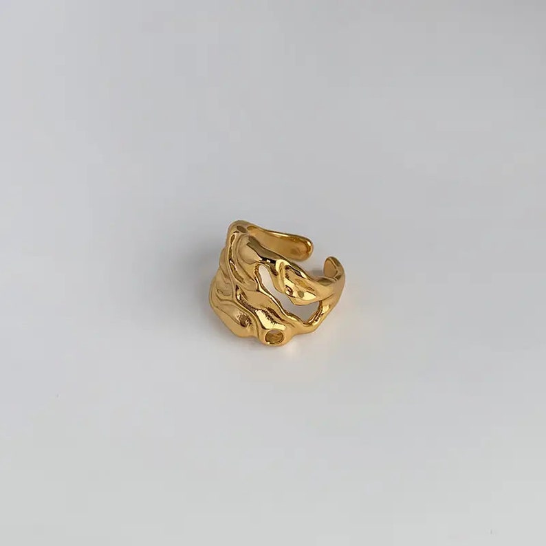K&ouml;nnte beinhalten: Goldring mit abstraktem, organischem Design. Der Ring ist aus dickem, strukturiertem Metall gefertigt und hat eine einzigartige, asymmetrische Form.