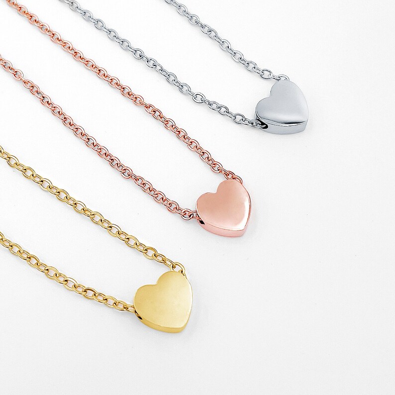 May include: Three delicate necklaces with heart-shaped pendants. The necklaces are in gold, rose gold, and silver.