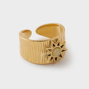 Puede incluir: Anillo ajustable de oro con una banda texturizada y un diseño en forma de estrella con una piedra de color amarillo claro en el centro.