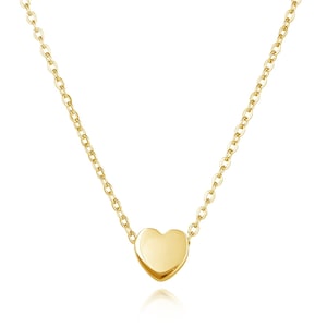 May include: A delicate gold chain necklace with a small, smooth heart pendant.