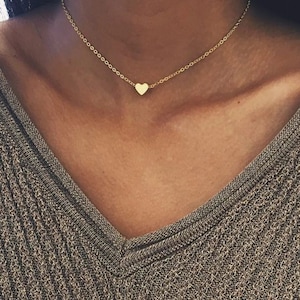 May include: A delicate gold chain necklace with a small heart pendant.