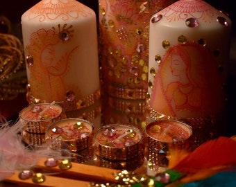 Puede incluir: Tres velas blancas en forma de pilar decoradas con purpurina rosa y dorada y diseños intrincados. Las velas están rodeadas de pequeñas velas de té y adornos dorados y rosados.