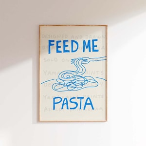 以下が含まれることがあります： 青い文字で「Feed Me Pasta」と書かれた、青と白の額装されたプリント。プリントには、フォークとスパゲッティの青い線画が描かれている。