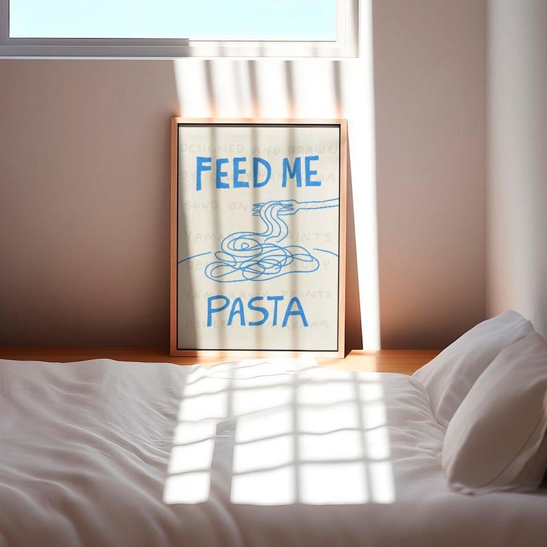 以下が含まれることがあります： ベージュの額縁に入ったプリントで、青い文字で「Feed Me Pasta」と書かれています。テキストの上に、フォークを持った手を青い線で描いた絵があり、フォークの先にはパスタの糸が乗っています。パスタはボウルに入っています。
