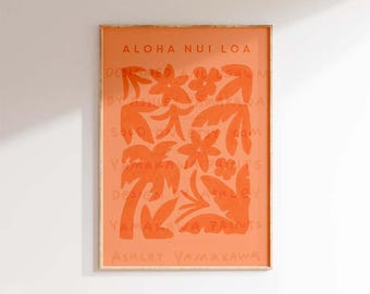 May include: A framed print with an orange background and a design of palm trees and flowers. The text "ALOHA NUI LOA" is at the top of the print. The artist's name, "ASHLEY YAMAKAWA", is at the bottom of the print.