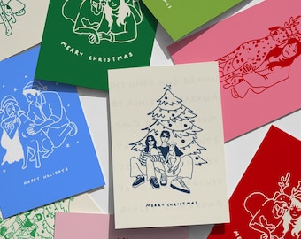 May include: A collection of Christmas cards in various colors, including green, pink, blue, and red. Each card features a white line drawing of people and animals, with holiday greetings like "Merry Christmas" and "Happy Holidays".