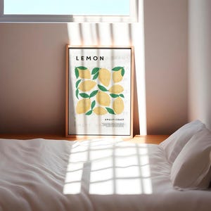 May include: A framed print with a white background and the word "LEMON" in black text. The print features a stylized illustration of lemons with green leaves. The text "Amalfi Coast" is at the bottom of the print.