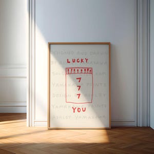 Peut inclure: Une affiche blanche avec du texte rouge qui dit "Designed and Drawn by Ashley Yamakawa" et "Solo Prints.com". L'affiche pr&eacute;sente une bo&icirc;te d'allumettes rouge avec le chiffre "7" &eacute;crit quatre fois &agrave; l'int&eacute;rieur. Le texte "Lucky" est au-dessus de la bo&icirc;te d'allumettes et "You" est en dessous de la bo&icirc;te d'allumettes. Le texte "Yamakawa Prints" et "Design Ashley" sont &eacute;crits sous la bo&icirc;te d'allumettes. Le texte "Ashley Yamakawa" est &eacute;crit en bas de l'affiche.